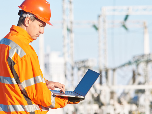 Engineer studies laptop overlooking mechanical project
